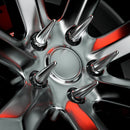 Close-up view of a custom black alloy wheel fitted with six chrome spike lug nuts, reflecting red highlights. The aggressive design showcases the sharp, pointed styling ideal for off-road or show vehicles